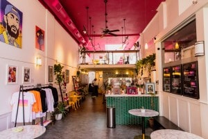 Colorful coffee shop with a pink ceiling, lofted seating area and green counter.