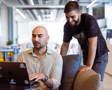 Two people are sitting at a table with laptops.