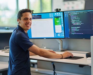 A person smiling while sitting in front of a computer.