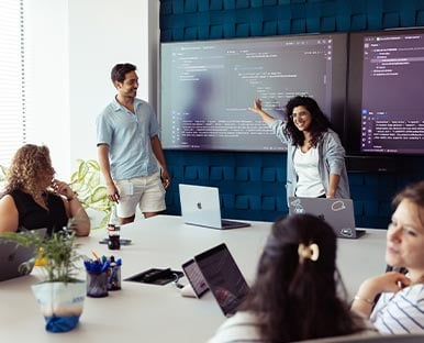 A group of people standing around a laptop computer.