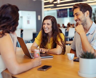 Three people sitting at a table with laptops.