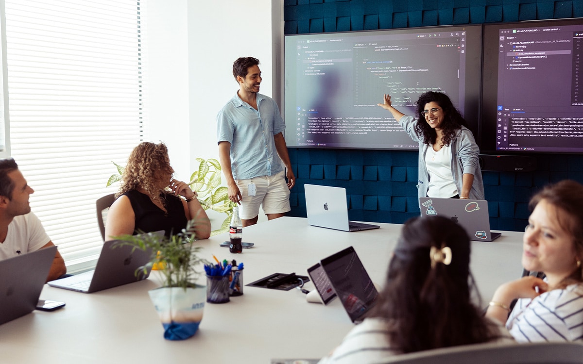 A group of people standing around a laptop computer.