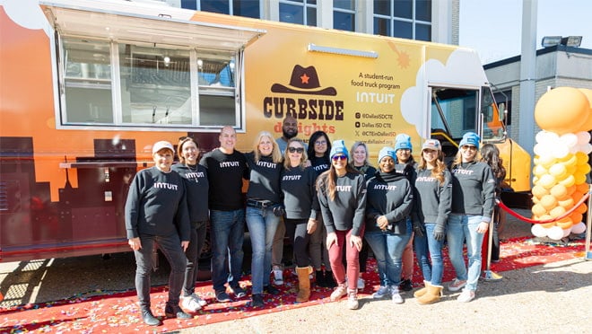 A group of people posing for a picture in front of a truck.