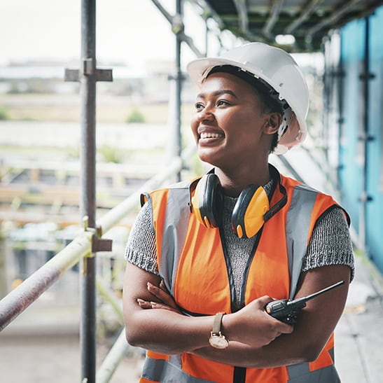 A woman in a hard hat and safety vest at a construction site. 