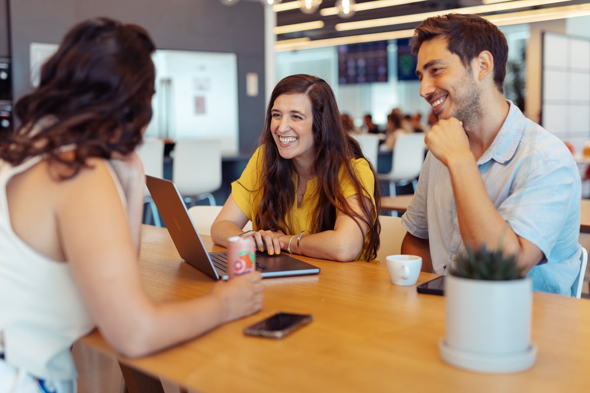 Three people sitting at a table with laptops.