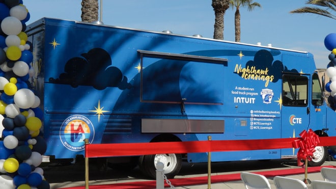 A blue truck with a large blue trailer behind it.