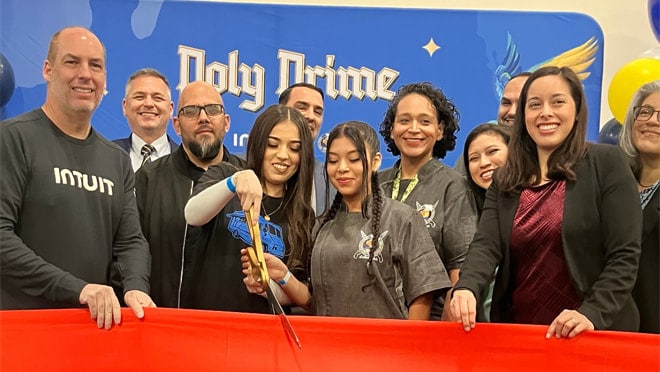 A group of people standing around a blue ribbon cutting a ribbon.