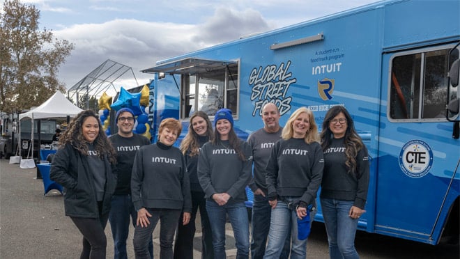 A group of people standing next to a blue truck.