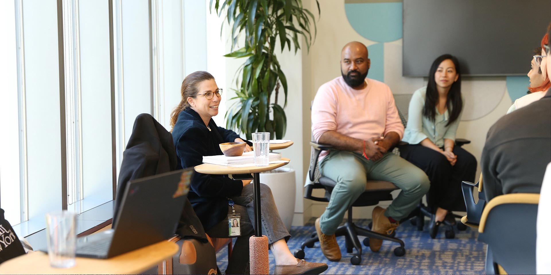 A group of people sitting around a table with laptops.