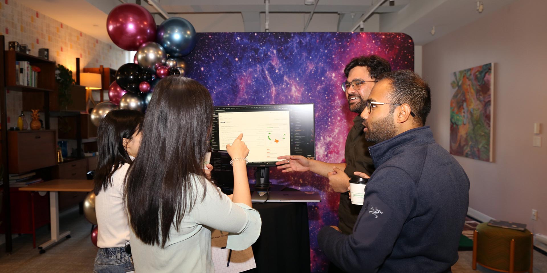 A group of people standing around a computer.